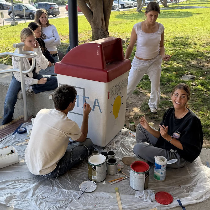 estudiantes pintando botes de basura